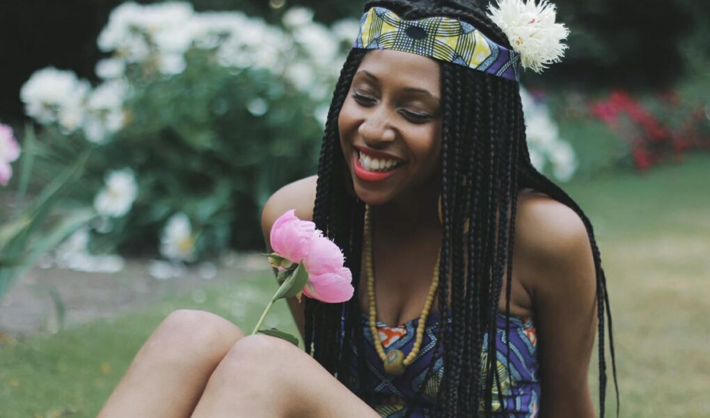 photography of a woman looking at flower