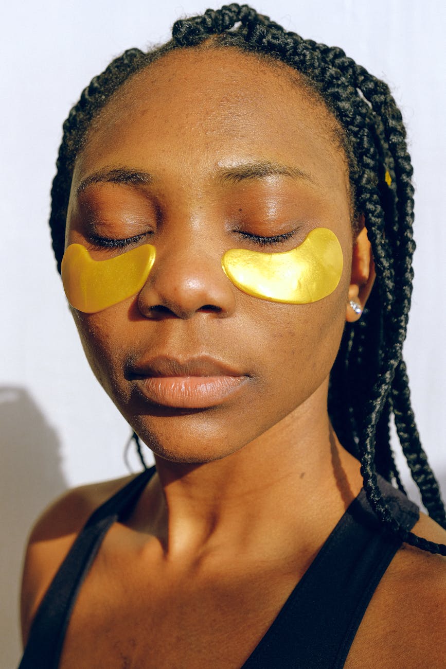 young peaceful black woman with golden patches under eyes