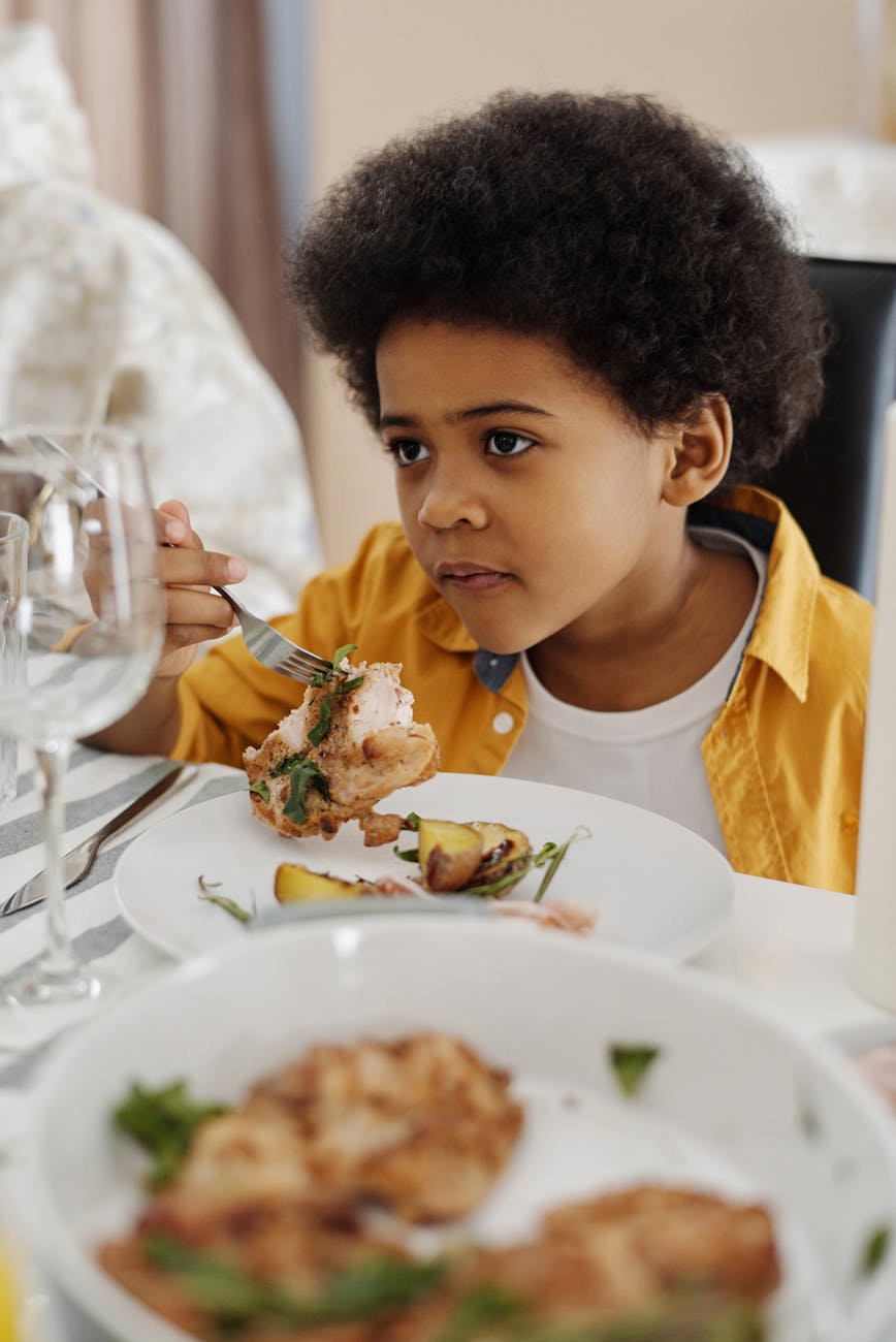 boy sitting at a table with food on his plate