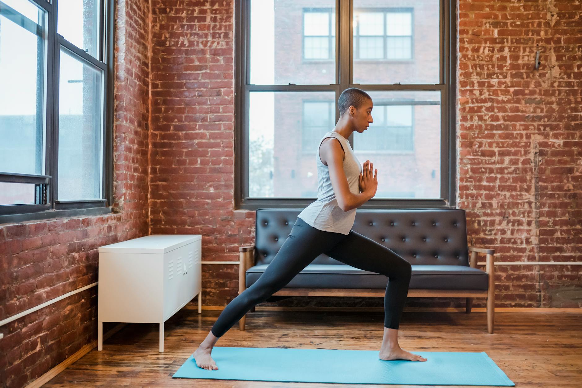 sporty black woman doing anjaneyasana posture