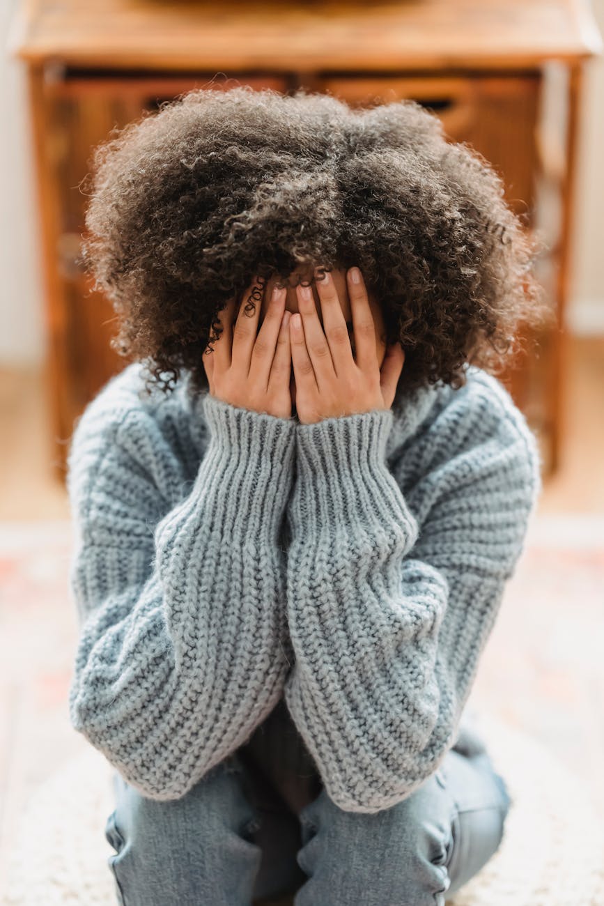 unrecognizable black woman covering face with hands