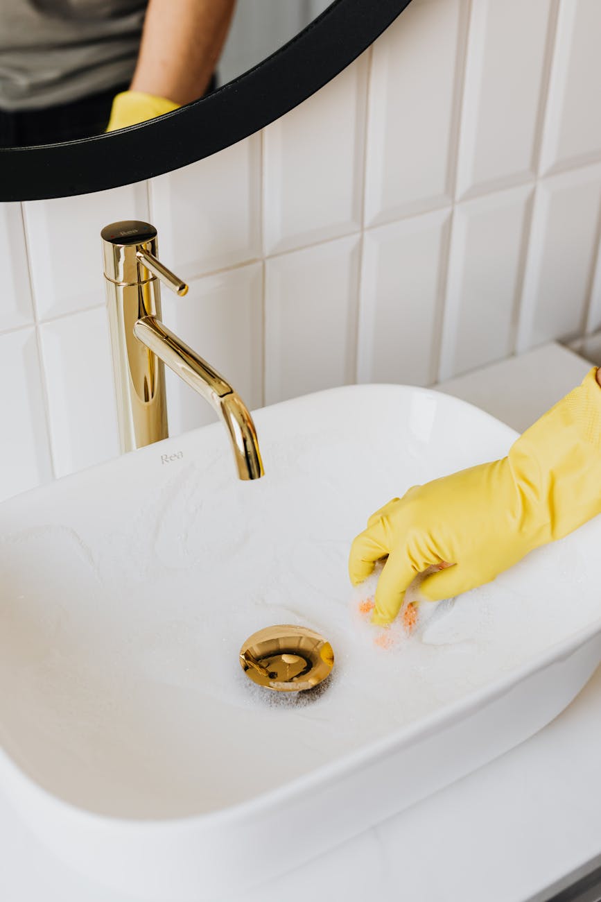 faceless man cleaning sink in bathroom