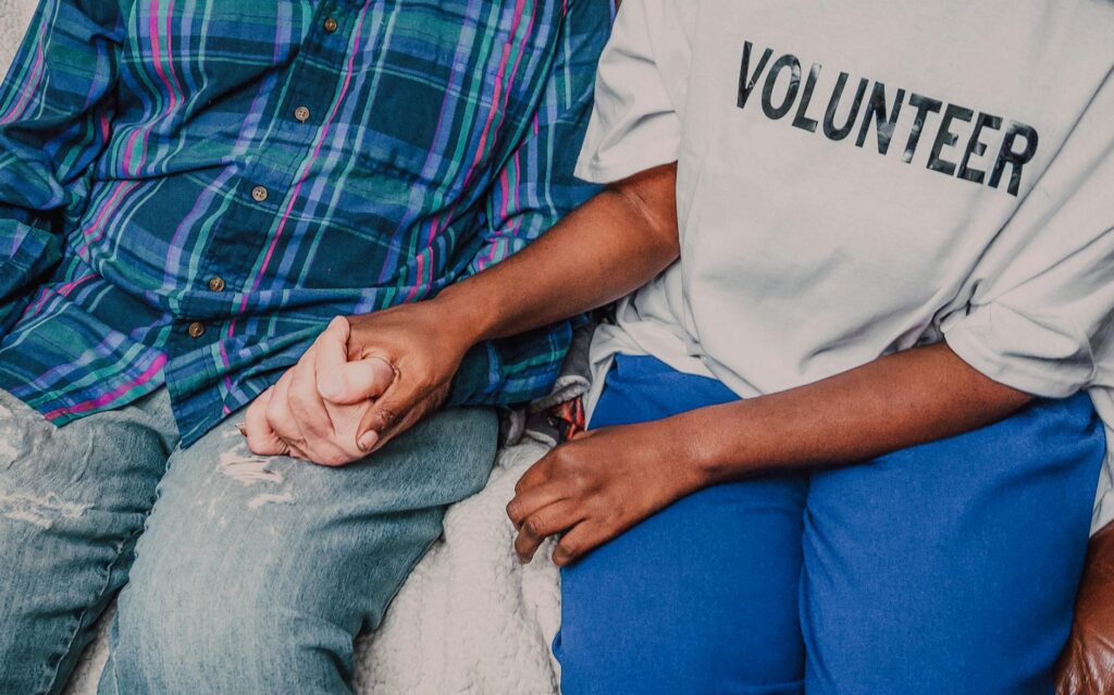 a person wearing volunteer shirt holding a persons hand