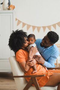 woman kissing a baby beside a man