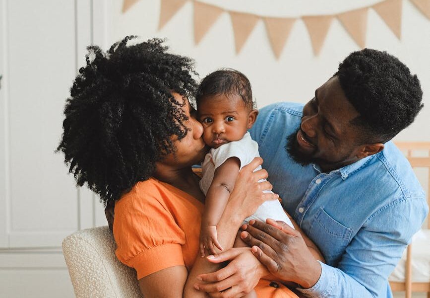 woman kissing a baby beside a man