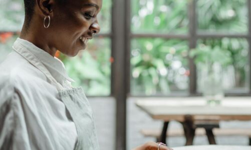 cheerful black woman sitting at table in restaurant