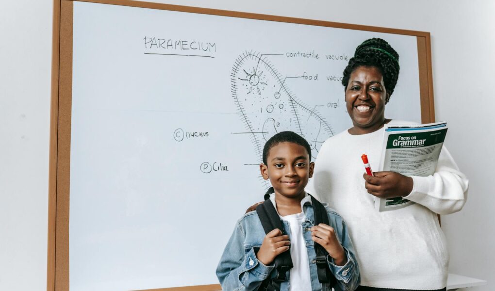 cheerful black woman with student against whiteboard