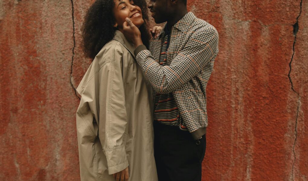 happy couple standing near a red wall