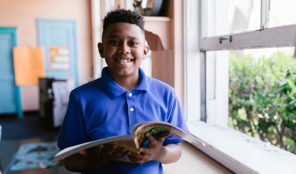 boy in blue polo shirt holding a open book