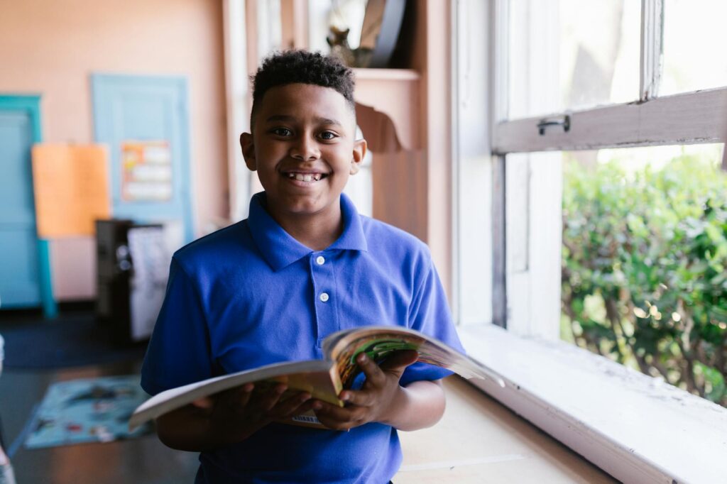 boy in blue polo shirt holding a open book